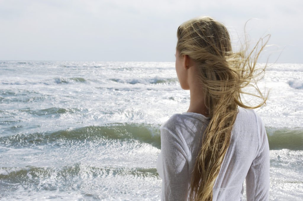 Young Woman Looking at Ocean wondering who she is after losing herself in a relationship or tragedy of life