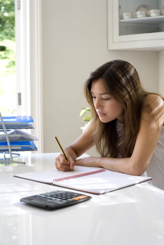 woman checking over her monthly expenses to reduce them so she can save more each month and find new methods to pay down debts