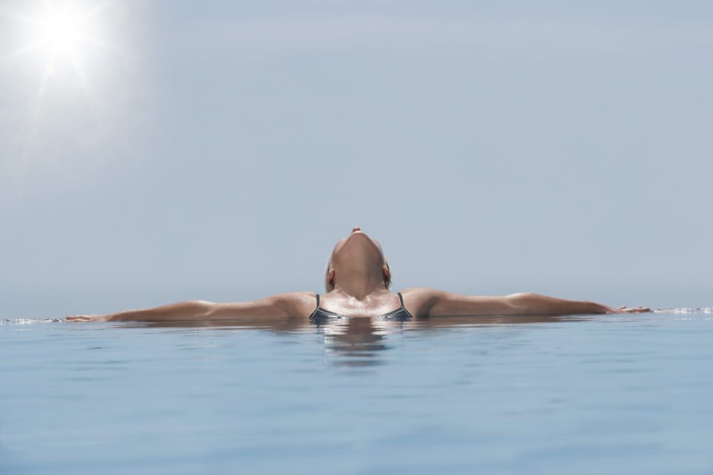 woman relaxing for self care in a pool or ocean soaking up the sun and enjoying the outdoors