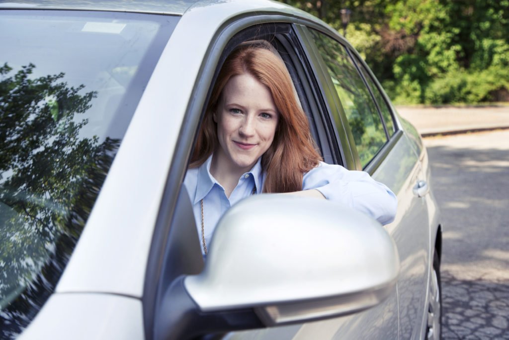 Teen girl driving her car, conducting a simple safety check to earn a full ride scholarship to college.