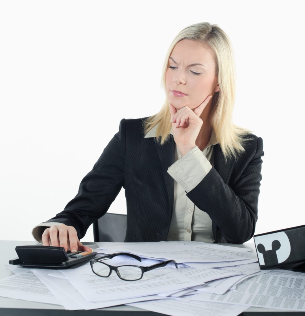 Woman working on an annual financial check up using her calculator and paperwork. 