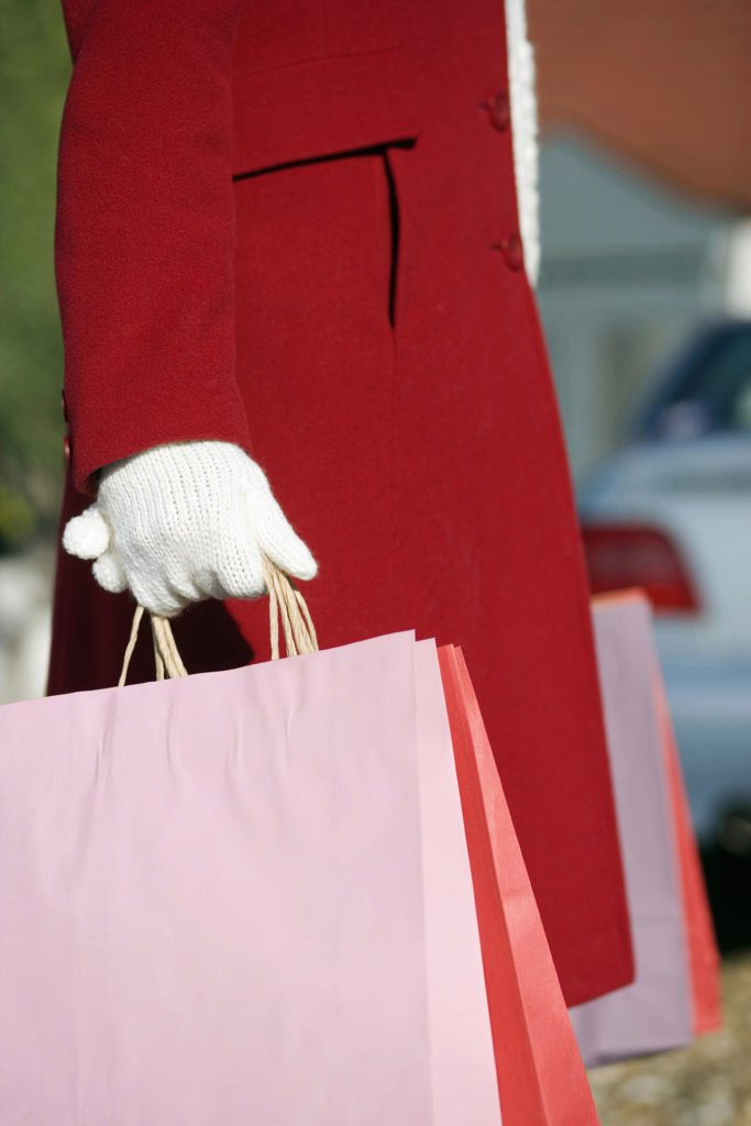 Woman in christmas coat carrying bags from holiday shopping, deciding to layaway or to put the purchases on credit