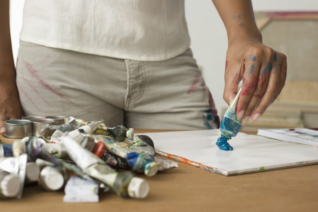 woman squeezing art onto a canvas